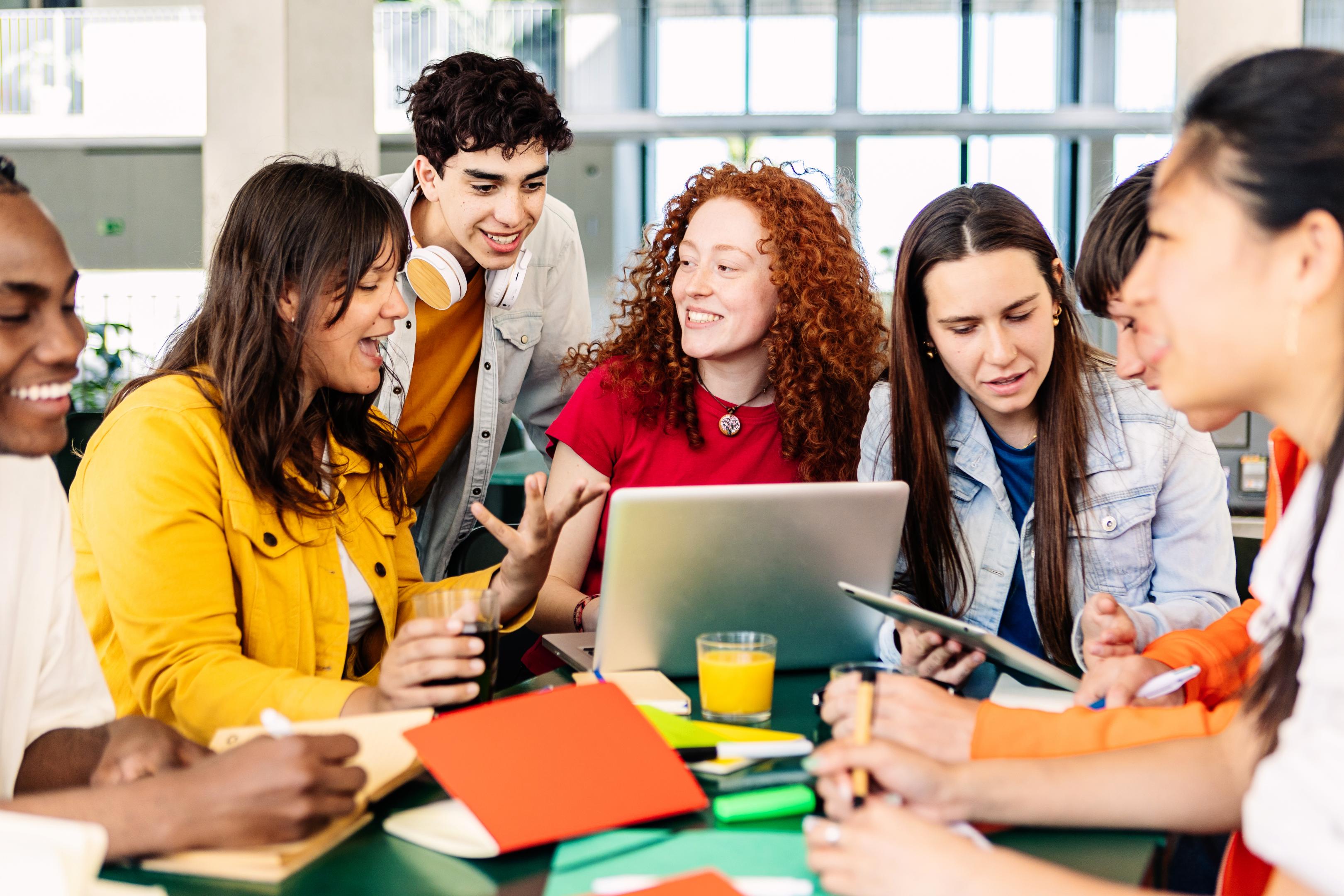 Schülerinnen und Schüler vor einem Computer, die Lehrkraft schaut über die Schulter