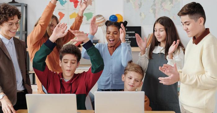 Schülerinnen und Schüler und Lehrerin freuen sich bei der Arbeit am PC